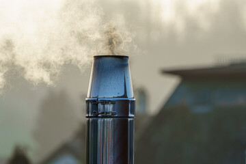 Chimney releasing smoke in a quiet neighborhood during early morning hours