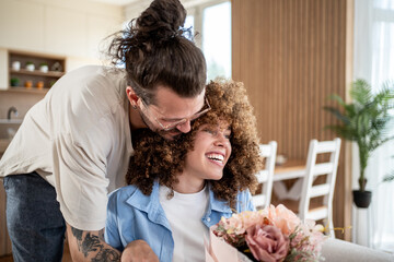 Man giving flowers to smiling woman at home