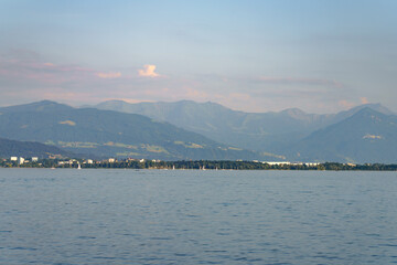 Mountain range and tranquil lake reflect evening light near a serene shoreline
