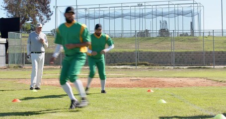 Senior coach whistling, signaling male baseball players shuffling around cones on field for agility - Powered by Adobe