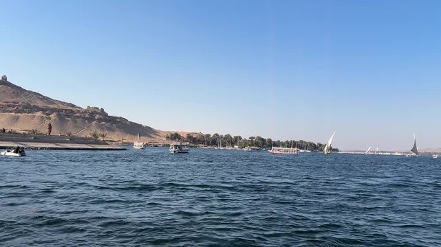Ancient rock-cut Tombs of the Nobles on the hillside across the Nile River from Aswan, Egypt, seen from a boat ride.