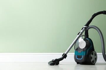 One vacuum cleaner on floor near green wall. Space for text