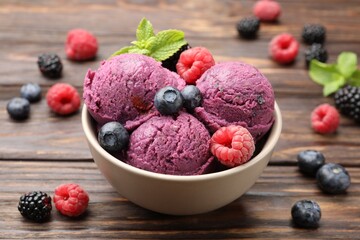 Delicious sorbet with fresh berries and mint in bowl on wooden table, closeup