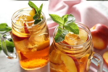 Refreshing iced peach tea with mint in mason jars on table, closeup