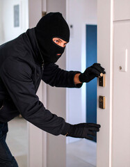 A stereotypical image of a thief: masked face, dressed in black, sneaky posture.