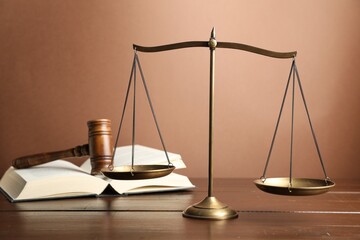 Scales of justice, gavel and book on wooden table, selective focus