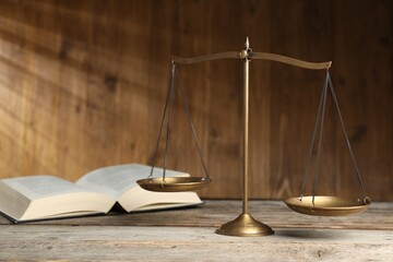 Scales of justice and book on wooden table