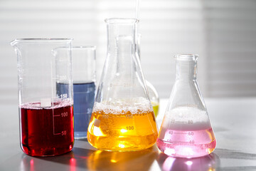 Laboratory glassware with different samples on light table indoors, closeup. Solution chemistry
