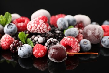 Many different frozen berries and mint on black table, closeup