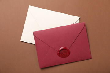 Envelopes with wax seal on brown background, top view