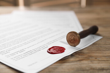 Documents with wax seal and stamp on wooden table, closeup