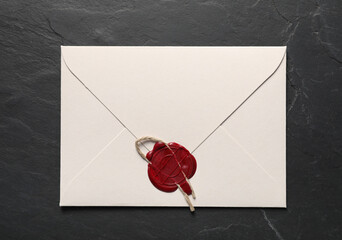Envelope with wax seal and twine on black table, top view