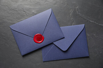 Envelopes with wax seal on black table, top view