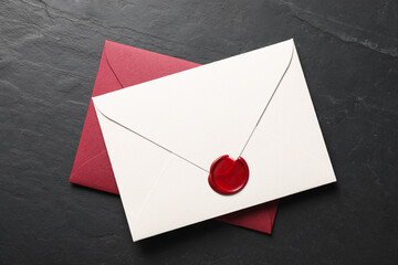 Envelopes with wax seal on black table, top view