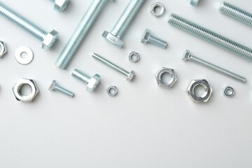 Metal bolts and nuts on white background, flat lay. Space for text