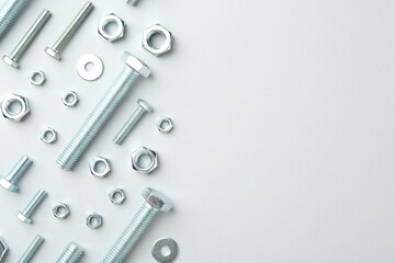 Metal bolts and nuts on white background, flat lay. Space for text
