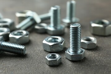 Metal bolts and nuts on grey table, closeup