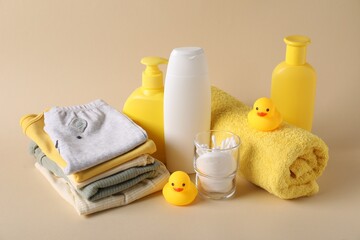 Baby accessories, clothes and body care products on beige background