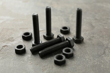 Metal bolts and nuts on grey table, closeup
