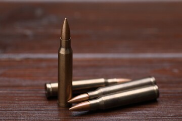 Many metal bullets on wooden table, closeup