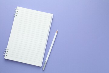 Open notepad and white pencil on violet background, flat lay. Space for text