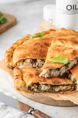 Traditional closed italian pizza calzone stuffed with chicken, mozzarella and spinach on light gray background