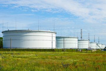 Large industrial oil storage tanks in field with blue sky at petroleum facility