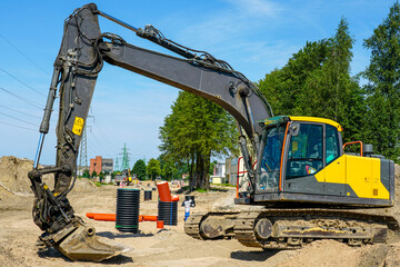 Excavator at construction site with pipes and manholes during urban infrastructure development