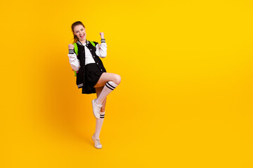Energetic teen girl celebrating enthusiastically against a bright yellow background, embodying...
