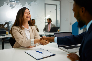 Fototapeta premium Happy businesswoman shaking hands with a businessman after successful job interview