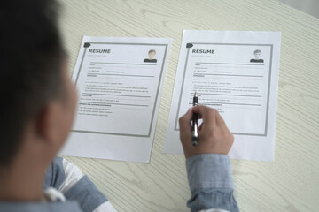 Asian businessman employer is holding resume to hire job applicant, analyzing the applicant's data and job history before nterview, recruiting new employees, recruitment, employment and HR concept.