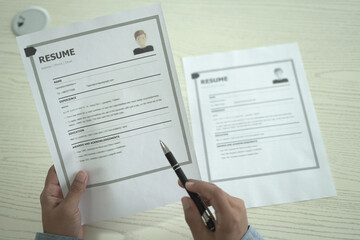 Asian businessman employer is holding resume to hire job applicant, analyzing the applicant's data and job history before nterview, recruiting new employees, recruitment, employment and HR concept.