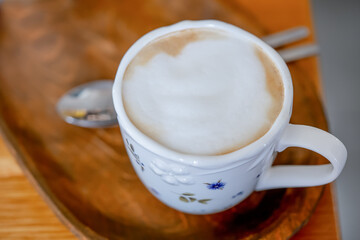 Beautiful white cappuccino cup with a spoon on a wooden breakfast tray 