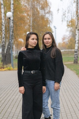 Portrait of two beautiful young twin sisters in an autumn park.