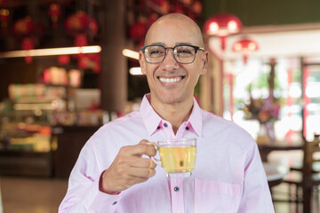 Bald Hispanic man wearing pink casual business shirt and eyeglasses in Chinese style tea house