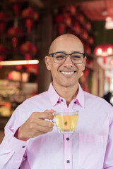 Bald Hispanic man wearing pink casual business shirt and eyeglasses in Chinese style tea house