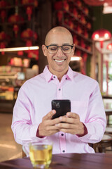 Bald Hispanic man wearing pink casual business shirt and eyeglasses in Chinese style tea house