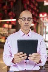 Bald Hispanic man wearing pink casual business shirt and eyeglasses in Chinese style tea house