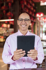 Bald Hispanic man wearing pink casual business shirt and eyeglasses in Chinese style tea house