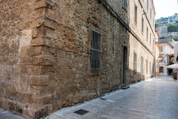 Historic building on a narrow paved street in Nafplio Greece with stone walls and barred windows