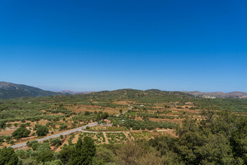 Fototapeta premium Vast agricultural landscape with olive groves, vineyards, and rural roads in Crete