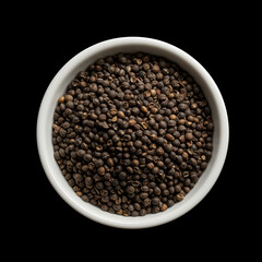 Top-down view of whole dried black peppercorns in a white ceramic bowl isolated on a black background. Culinary spice for seasoning.