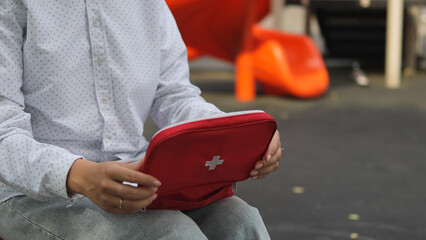First aid kit. Children's playground. Woman and first aid kit. High quality photo.