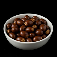 Obraz premium A bowl full of fresh acorns on a black background, perfect for autumn crafting and decoration