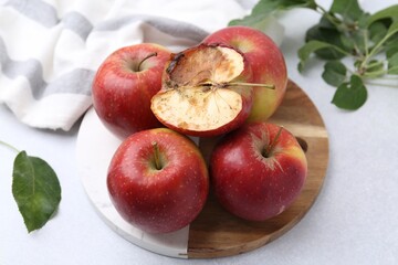 Spoiled apple and good ones on white table, closeup