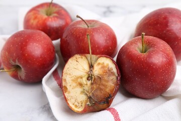 Spoiled apple and good ones on white table, closeup