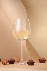 Delicious truffle bonbons and wine on beige background