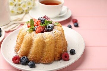 Delicious bundt cake with powdered sugar, berries and mint on pink wooden table, closeup