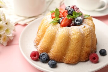 Delicious bundt cake with powdered sugar, berries and mint on pink wooden table, closeup