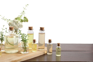 Bottles of essential oils and different herbs on wooden table against white background
